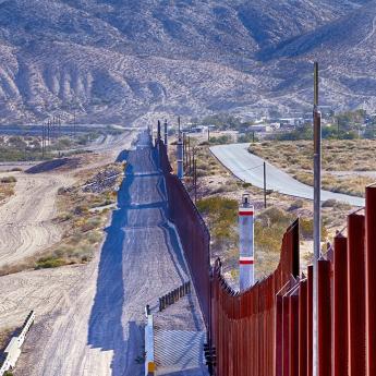 Photo of border wall with mountains in the background
