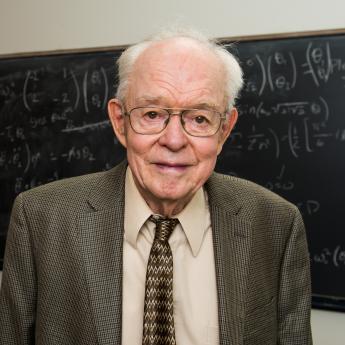 Prof. Parker in front of blackboard with equations