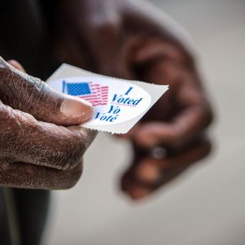 Black voter holding an "I voted" sticker