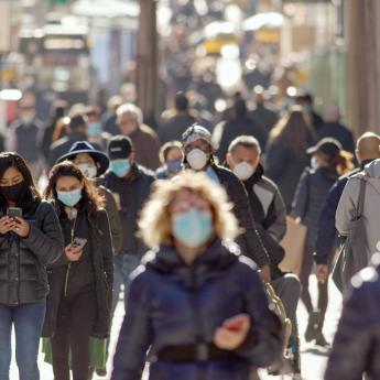 A street crowded with people wearing protective masks.