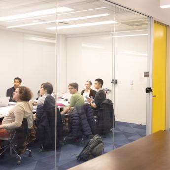Students sit together inside a glass-walled meeting room inside UChicago's Crerar Library