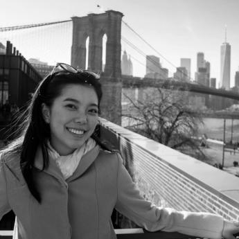 Assistant Professor Maggie Shi stands in front of the Brooklyn Bridge