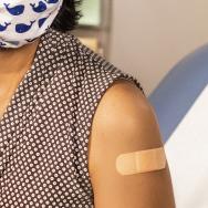 Woman wearing a face mask with a bandaid on her arm