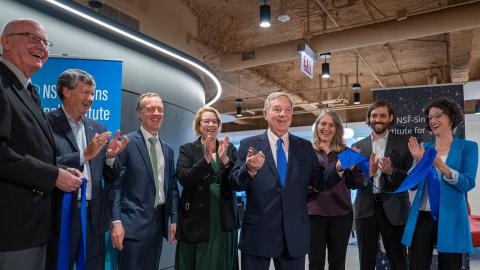 A group of people around Senator Dick Durbin, all standing in a new science center during a ribbon-cutting ceremony.