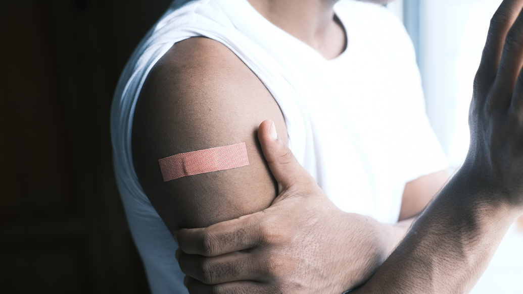 An adhesive bandage on arm, signifying the completion of a COVID-19 vaccine dose
