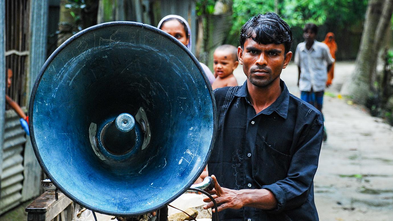 A man with a portable megaphone in rural Bangladesh
