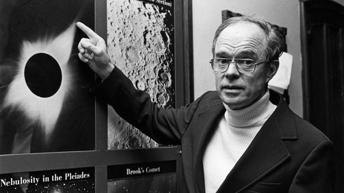 Eugene Parker, pictured in 1977, pointing to a poster of a solar eclipse