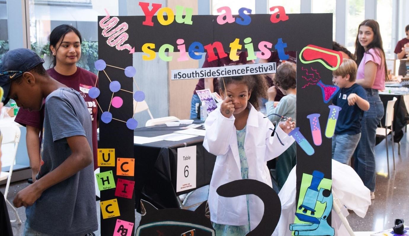 Girl poses in lab coat at science fest 