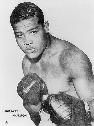 Black and white image of boxer Joe Louis standing in a fighter pose. 