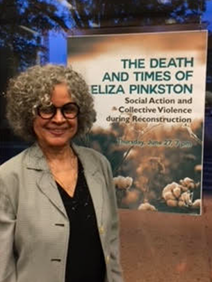Julie Saville stands in front of poster that reads: The Death and Times of Eliza Pinkston: Social Action and Collective Violence during Reconstruction