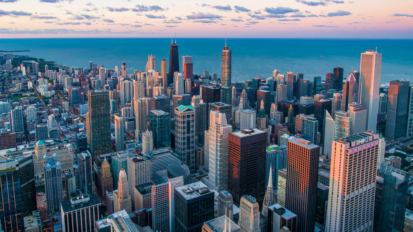 Aerial photograph of the skyscrapers of downtown Chicago with the lake visible behind, at sunset