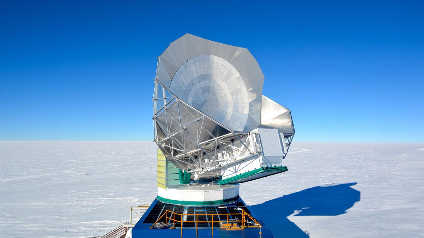 Photo in the daytime of the South Pole Telescope, a large telescope in the middle of a snowfield