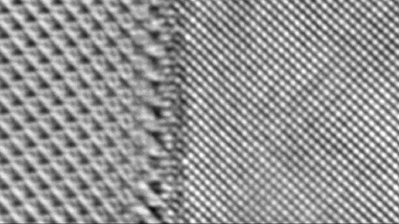 Black and white microscope image of two repeating lattices of atoms with a seam in the middle