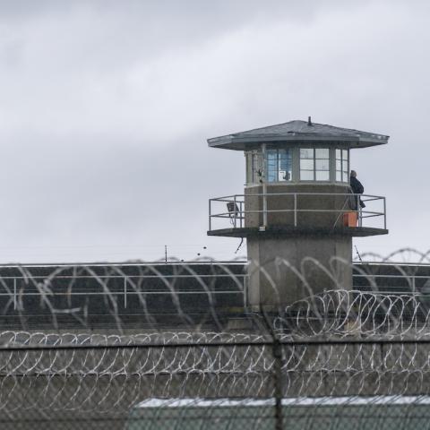 Wide shot of a prison watch tower, with barbed wire in the foreground