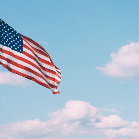 The American flag flying against a blue sky