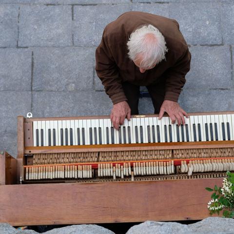 Man plays an old piano outside