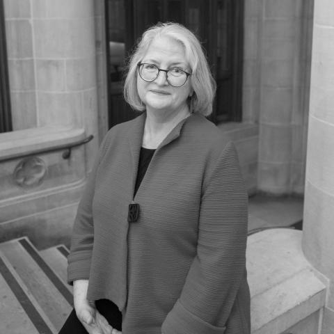 Professor Elisabeth Clemens, a woman with shoulder length hair and glasses, sits for a photo with crossed hands