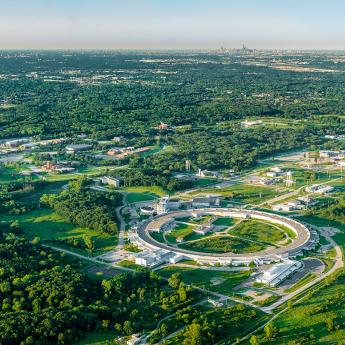 Aerial image of the Advanced Photon Source, a large circular building, with the Chicago skyline in the distance