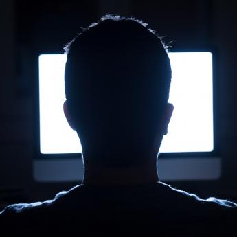 Man sitting at computer in dark room