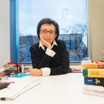 Prof. Giulia Galli sits in her office with a pile of textbooks and a model of molecules.