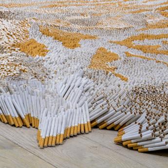 A detailed shot of Xu Bing's "1st Class," which uses cigarettes to mimic a tiger-skin rug.