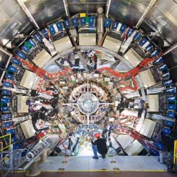 Large circular detector framework at the Large Hadron Collider with worker in foreground