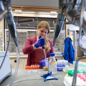 Scientist works in lab holding pipette