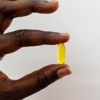 Hand holding a Vitamin D capsule
