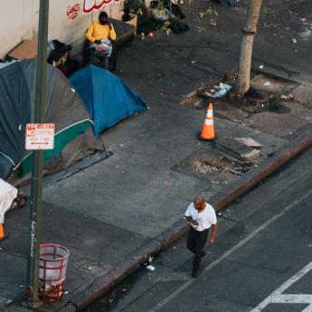 A man walks by a group of tents along a street