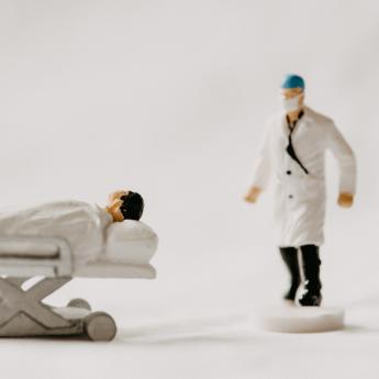 Figurines of health care workers next to a figurine of a patient on a wheeled gurney