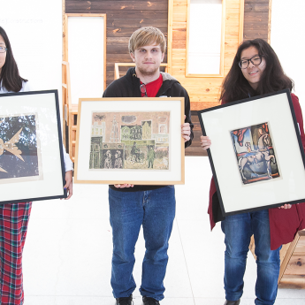 Students holding framed pieces of art