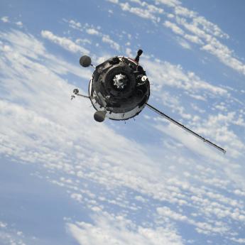 A satellite in orbit above blue sky and clouds