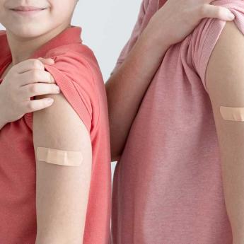 Child and parent pose with their COVID vaccination bandages