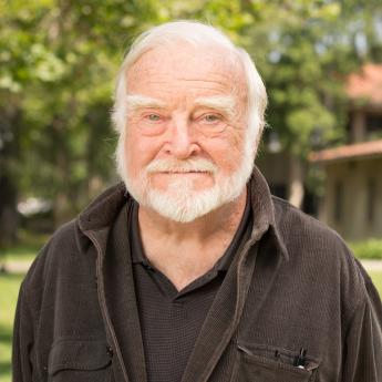 Mihaly Csikszentmihalyi stands on the campus of Claremont Graduate University