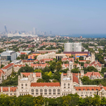 An aerial view of the UChicago campus, facing north with the Chicago downtown skyline in the distance