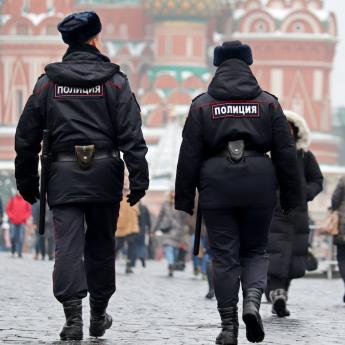 Scene of police and Russian citizens walking in Moscow's Red Square, with St. Basil's Cathedral in the background