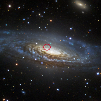 Telescope image of large galaxy with small spot circled