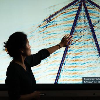 Prof. Sunyoung Park in front of a large screen showing wave patterns 