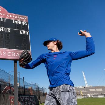 Wilson Cunningham warms up his pitch while standing in front of the UChicago scoreboard
