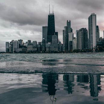 Lake Michigan flooding a concrete walkway in view of the Chicago skyline