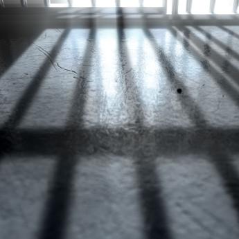 Bars of a jail cell cast shadows on the ground