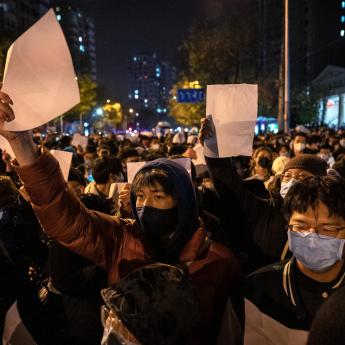 A group of protesters holds up blank pieces of white paper