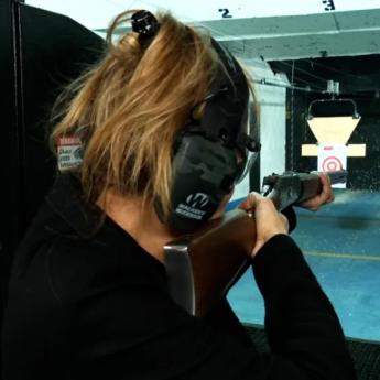 Rear view of a person firing a rifle at a shooting range