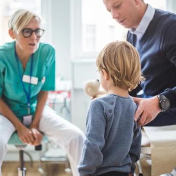 A doctor leans down to speak to a child