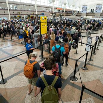 Passengers stand in line with bags at the airport