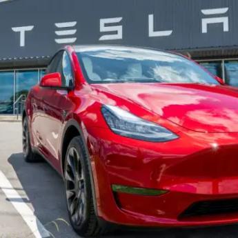 A cherry red Tesla sits in front of a Tesla storefront