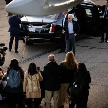 President Biden walks toward a crowd of reporters with his Secret Service detail trailing behind