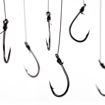 Closeup of several fishhooks dangling on a white background