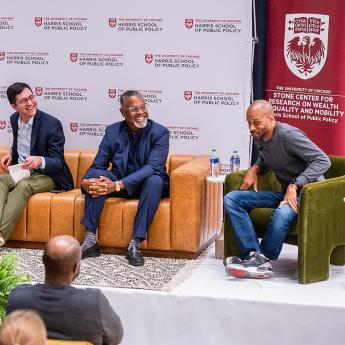 Panelists talk on stage at the Harris School of Public Policy