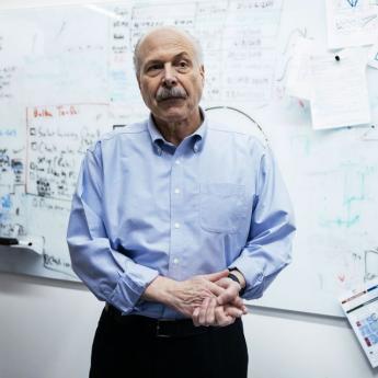 David Awschalom, a man with a mustache wearing a blue dress shirt, stands before a whiteboard